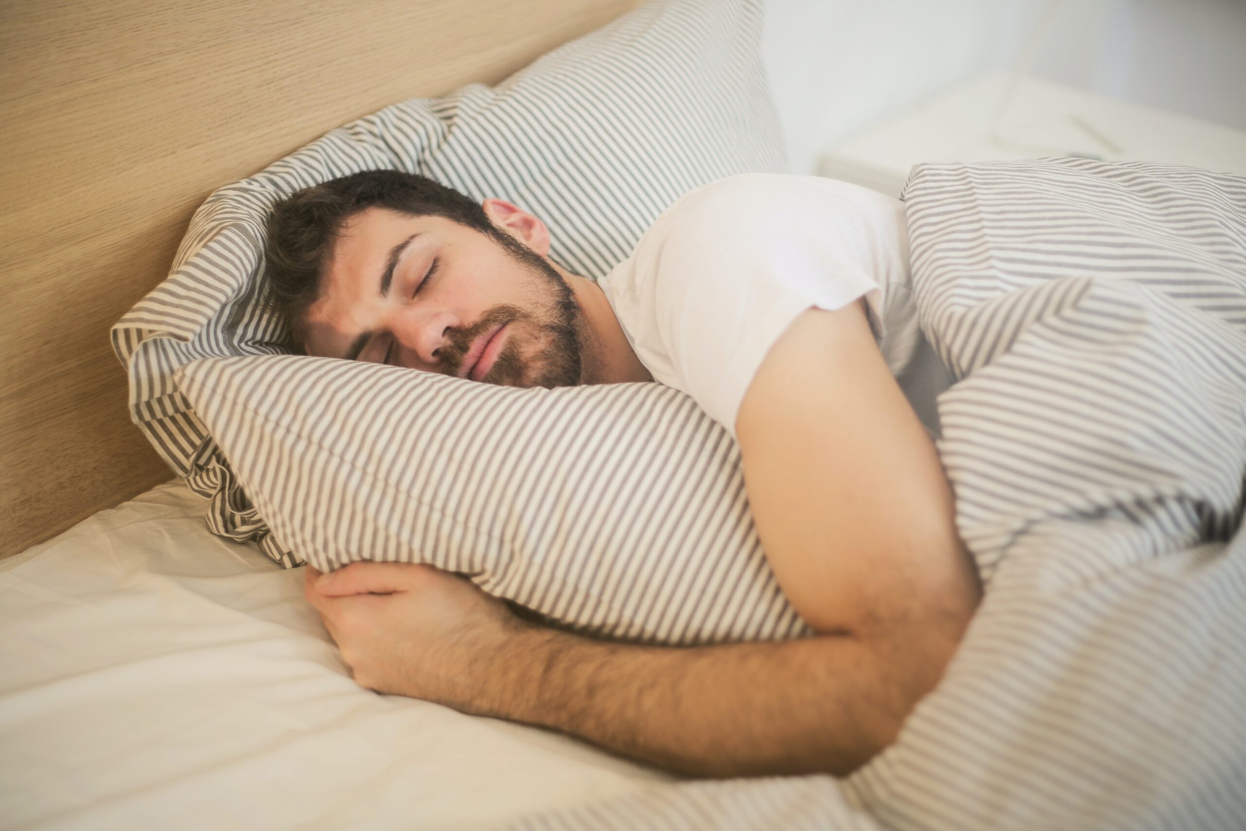 How to sleep better and faster? 8 Pro Tips An image of a man peacefully asleep on a comfortable bed, wrapped in blankets with a serene expression on his face."
